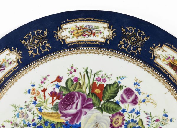 MANIFATTURA DEL XX SECOLO : Grande piano circolare in ceramica dipinto e decorato nello stile di Limoges con trionfo di fiori al centro, fascia esterna a fondo blu con riquadri raffiguranti nature morte di strumenti musicali  - Asta Asta 469 | ARTE ANTICA E DEL XIX SECOLO Online - Associazione Nazionale - Case d'Asta italiane