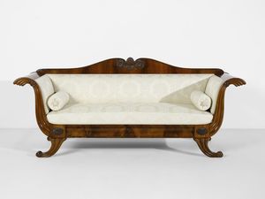 MANIFATTURA DEL XIX SECOLO - Divano lastronato in mogano, schienale di forma mossa con decori neoclassici, gambe arcuate