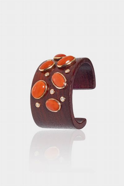 BRACCIALE : rigido in legno curvato  sommità con ovali in corallo rosso mediterraneo cabochon e oro rosa 9 Kt. Diamanti taglio brillante per totali ct 0 21 ca Corredato di certificato del perito Caviglia di Roma  - Asta Gioielli  - Associazione Nazionale - Case d'Asta italiane
