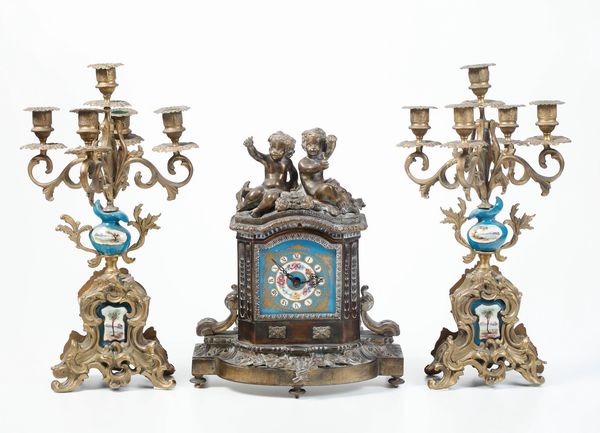 Trittico composto da pendola da tavolo e coppia di candelabri. Francia XX secolo  - Asta Antiquariato - Associazione Nazionale - Case d'Asta italiane