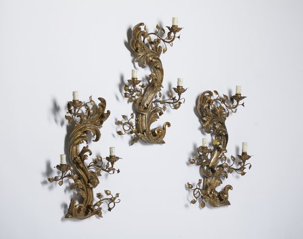 MANIFATTURA DEL XVIII-XIX SECOLO : Tre appliques in legno e metallo dorato, corpo centrale arcuato intagliato a motivo fitomorfo da cui si dipartono bracci in foggia di rami fogliati e fioriti  - Asta Asta 502 | ARTE ANTICA E DEL XIX SECOLO Online - Associazione Nazionale - Case d'Asta italiane