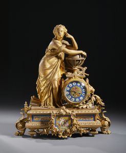 MANIFATTURA FRANCESE DEL XIX-XX SECOLO - Orologio da tavolo in metallo dorato con allegoria dell'Astronomia, quadrante e decori in ceramica smaltata