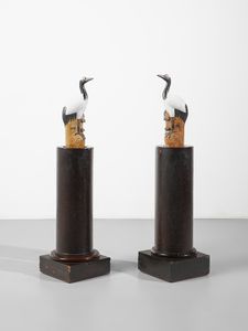 MANIFATTURA CINESE DEL XX SECOLO - Coppia di aironi in ceramica policroma e invetriata, assemblati su colonne in legno patinato di differente manifattura