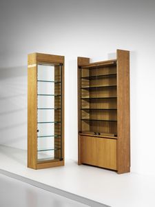 RIVADOSSI GIUSEPPE (n. 1935) - Lotto composto da una libreria a due ante con vetrinetta a cinque ripiani mobili e un mobile espositore da centro a sei ripiani mobili per Officina Rivadossi, Nave