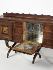 MANIFATTURA ITALIANA : Buffet a sei cassettini, due stipi e vano bar centrale con apertura a ribalta decorati con altorilievi raffiguranti un fanciullo con ariete  - Asta Asta 516 | DESIGN E ARTI DECORATIVE DEL NOVECENTO Online - Associazione Nazionale - Case d'Asta italiane