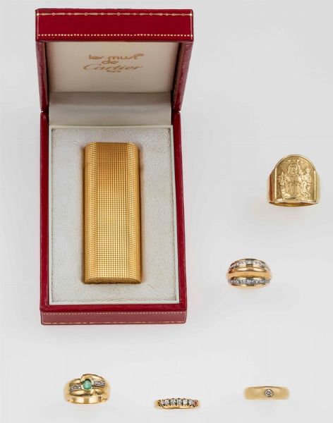 Lotto composto da un accendino Cartier placcato oro e cinque anelli con diamanti ed un piccolo smeraldo  - Asta Fine Jewels - Associazione Nazionale - Case d'Asta italiane