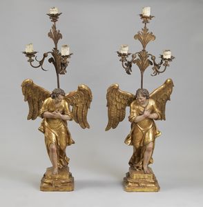 MANIFATTURA ITALIANA DEL XVII SECOLO - Coppia di angeli porta cero in legno intagliato, dorato e policromo, con candelabri in metallo dorato.