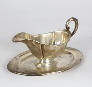 ARGENTIERE DEL XX SECOLO - Salsiera in argento con manico sagomato poggiante su un vassoio ovale.