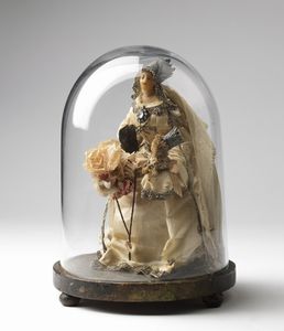ARTISTA DEL XIX SECOLO - Madonna con il Bambino con volti in agata, corone in metallo argentato, fiori in cartapesta e vestito in seta, sotto una campana di vetro.