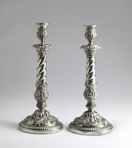 ARGENTIERE DEL XIX SECOLO - Coppia di candelabri in argento sbalzato e cesellato a motivi floreali e vegetali, base circolare.