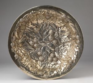 BUCCELLATI MARIO - Centrotavola in argento sbalzato e cesellato, fondo decorato a motivi vegetali e bordo liscio.