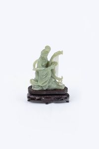 STATUINA IN GIADA - H cm 11 5 raffigurante figura femminile intenta nel suonare una cetra (mancanze). Poggiante su base in legno