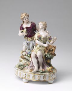MANIFATTURA VIENNESE DEL XIX SECOLO - Gruppo in porcellana, due figure e colomba con ricca decorazione floreale a smalti policromi su base ovale con profili dorati.