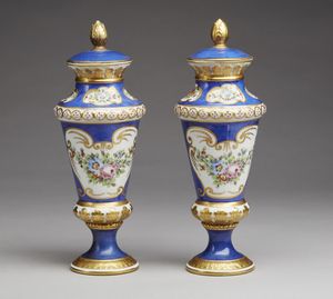 MANIFATTURA DI SEVRES DEL XIX SECOLO - Coppia di vasi con coperchi in porcellana parzialmente dorata e dipinta nei toni dell'azzurro e a decori floreali, poggianti su basi circolari.