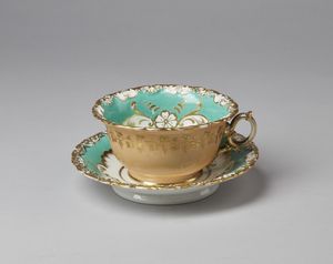 MANIFATTURA JACOB PETIT (1796 - 1868) - Tazza e piattino in porcellana dipinta a motivi floreali e parzialmente dorata.