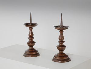 MANIFATTURA DEL XIX SECOLO - Coppia di candelieri in bronzo, corpo a rocchetto su base circolare modanata.