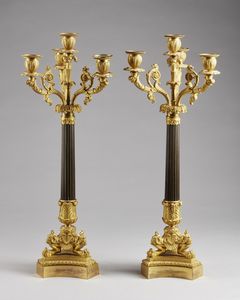 MANIFATTURA FRANCESE DEL XIX SECOLO - Coppia di candelieri a quattro fiamme in bronzo dorato e brunito, fusto scanalato poggiante su piedi leonini.