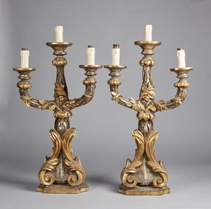 MANIFATTURA DEL XVIII SECOLO - Coppia di candelieri a tre fiamme in legno scolpito, dorato e argentato.