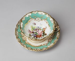 MANIFATTURA JACOB PETIT (1796 - 1868) - Tazza e piattino in porcellana dipinta a motivi floreali e parzialmente dorata.