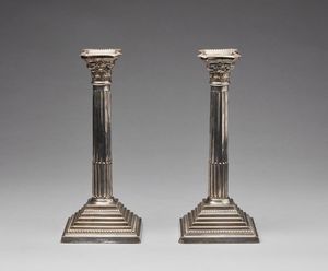 ARGENTIERE INGLESE DEL XX SECOLO - Coppia di candelieri in argento sterling e lamina d'argento in forma di colonne corinzie, su base quadrata in legno.